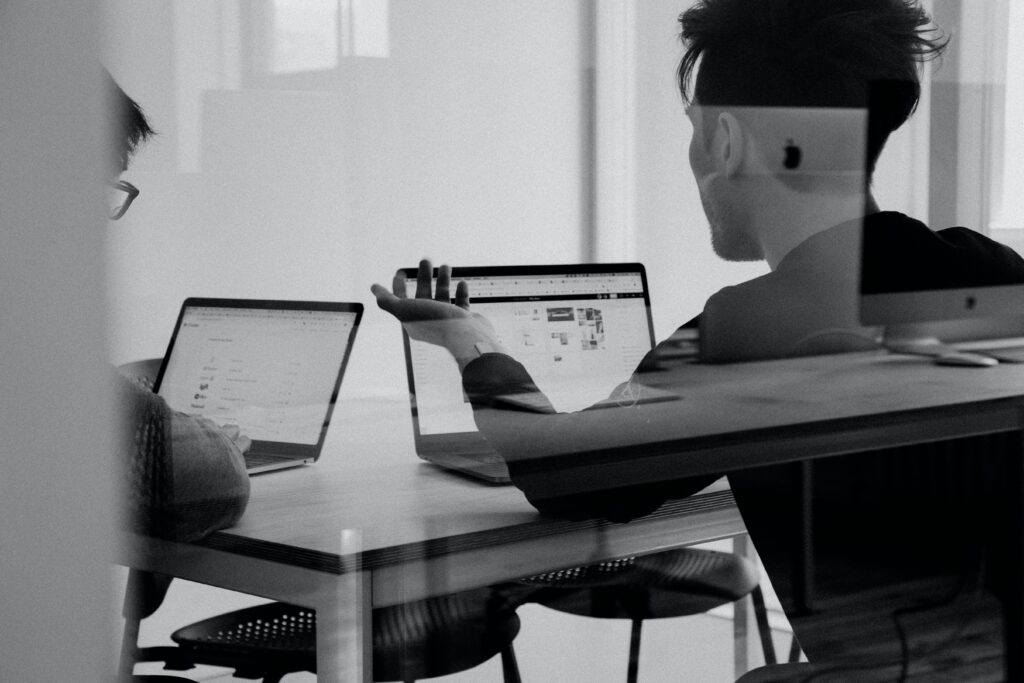 2 men discussing what is SEO while working on their laptops.