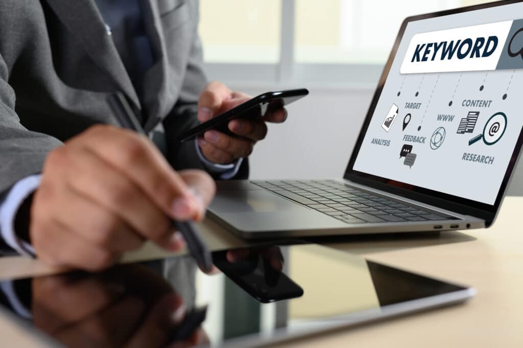 Man working on a website's keyword research on his laptop, tablet and phone.